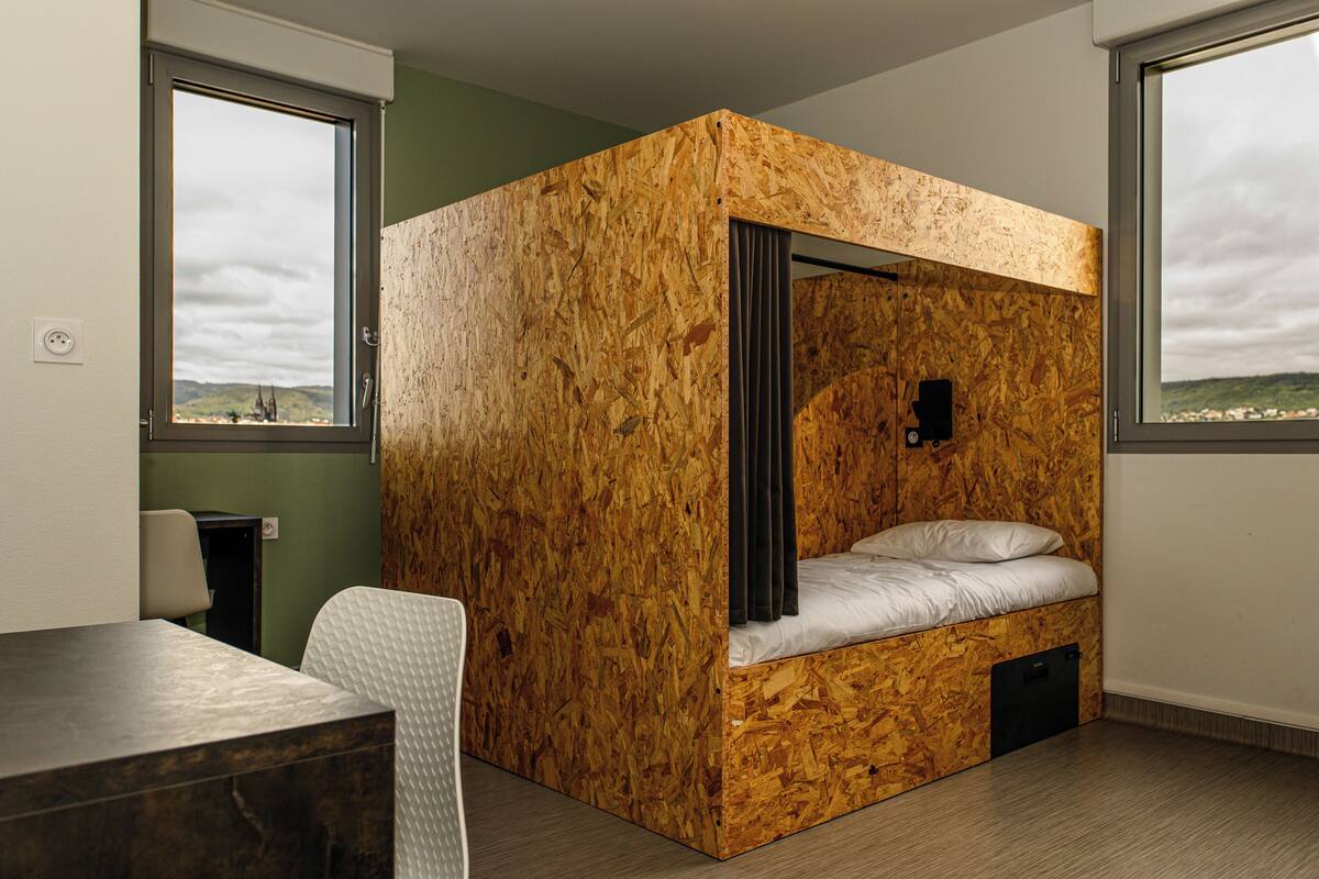 A compact room with a bunk bed, a desk, and a chair.