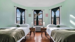 Une chambre avec deux lits, un radiateur et une fenêtre avec des rideaux.