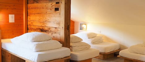 A wooden cabin with a mirrored wall reflecting a bed and a bench.