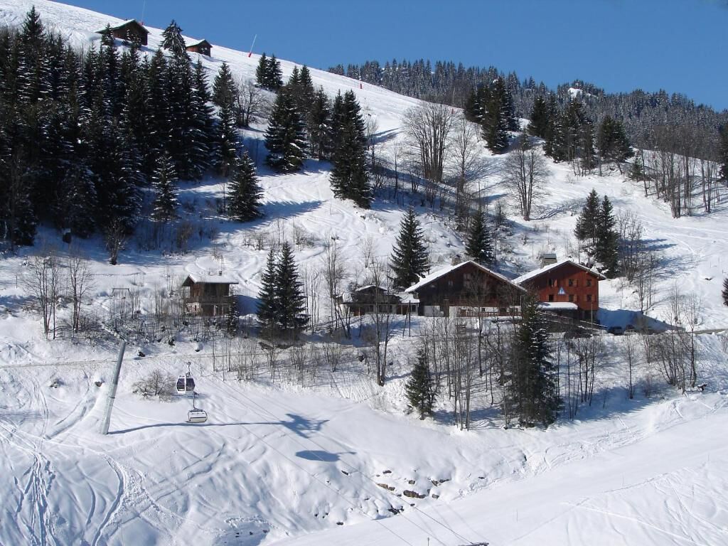 A snow-covered ski resort with cabins, ski lifts, and a clear blue sky.