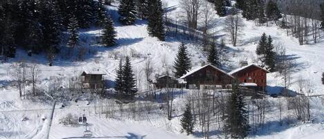 A snow-covered ski resort with cabins, ski lifts, and a clear blue sky.
