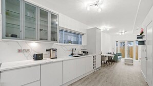 Una cocina moderna con armarios blancos, horno empotrado y ventana sobre el fregadero.