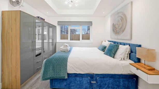 Un dormitorio con cama, armario, ventana y ventilador de techo.