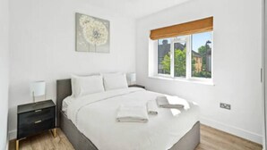 Un dormitorio con cama, mesita de noche, ventana con vistas y lámpara en el techo.