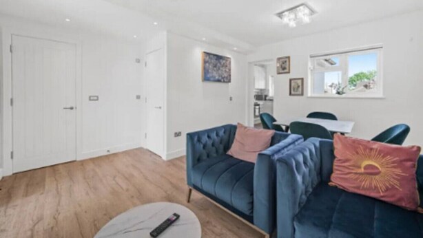 Una sala de estar moderna con un sofá azul, una pequeña mesa redonda y una puerta blanca.