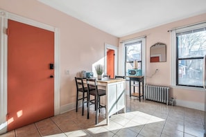 Une cuisine avec une porte rouge, un coin repas avec des chaises, un four à micro-ondes et une fenêtre donnant sur un beau paysage.
