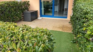 A modern building with a sliding glass door entrance, a small outdoor seating area, and well-maintained greenery. - Nice place with sea and swimming pool (Saint-Raphaël)
