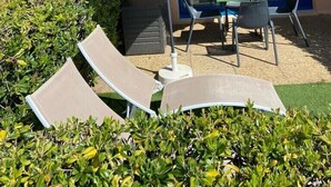 An outdoor seating area with a table and chairs under a canopy, surrounded by greenery. - Nice place with sea and swimming pool (Saint-Raphaël)
