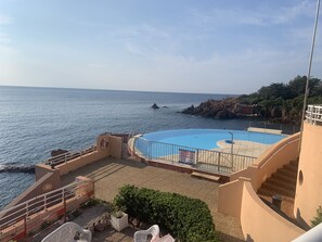 A pool area with a view of the sea, a staircase, and a small garden with plants.