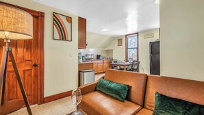 A living room with a brown leather sofa, a floor lamp, and a glass of wine on a side table.