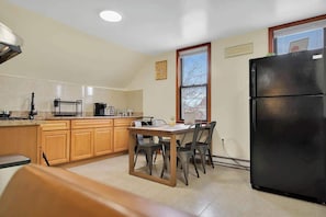 A kitchen with wooden cabinets, a black refrigerator, and a dining table with chairs.