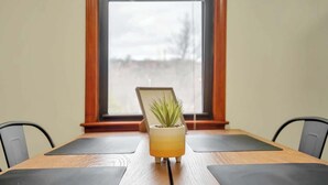 A wooden table with a potted plant in the center, two black mats on either side, and a window in the background.