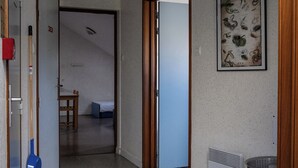 Un pasillo con una puerta de madera, un cuadro en la pared, un radiador y un bote de basura.