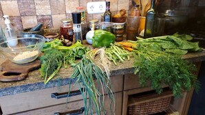 Una encimera de cocina con diversos vegetales frescos, un tazón de granos y utensilios de cocina.
