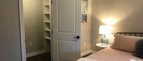A bedroom with a bed, a bedside lamp, and a closet with shelves.