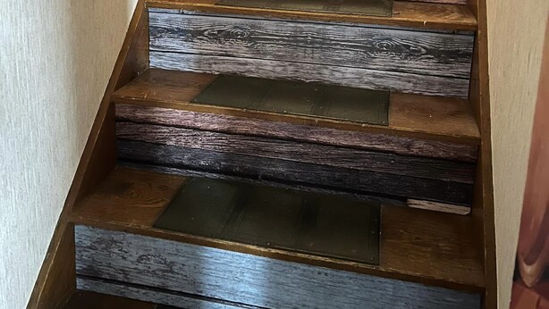 A wooden staircase with a modern design, featuring a combination of dark and light wood planks.