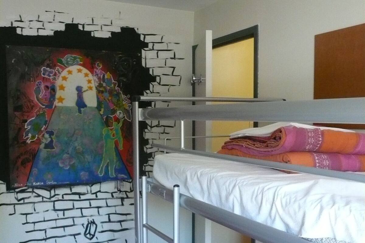 A bunk bed room with a mural on the wall, a door, and a window.