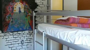 Une chambre avec un lit superposé, un mur décoré d’une fresque, une porte et une fenêtre.