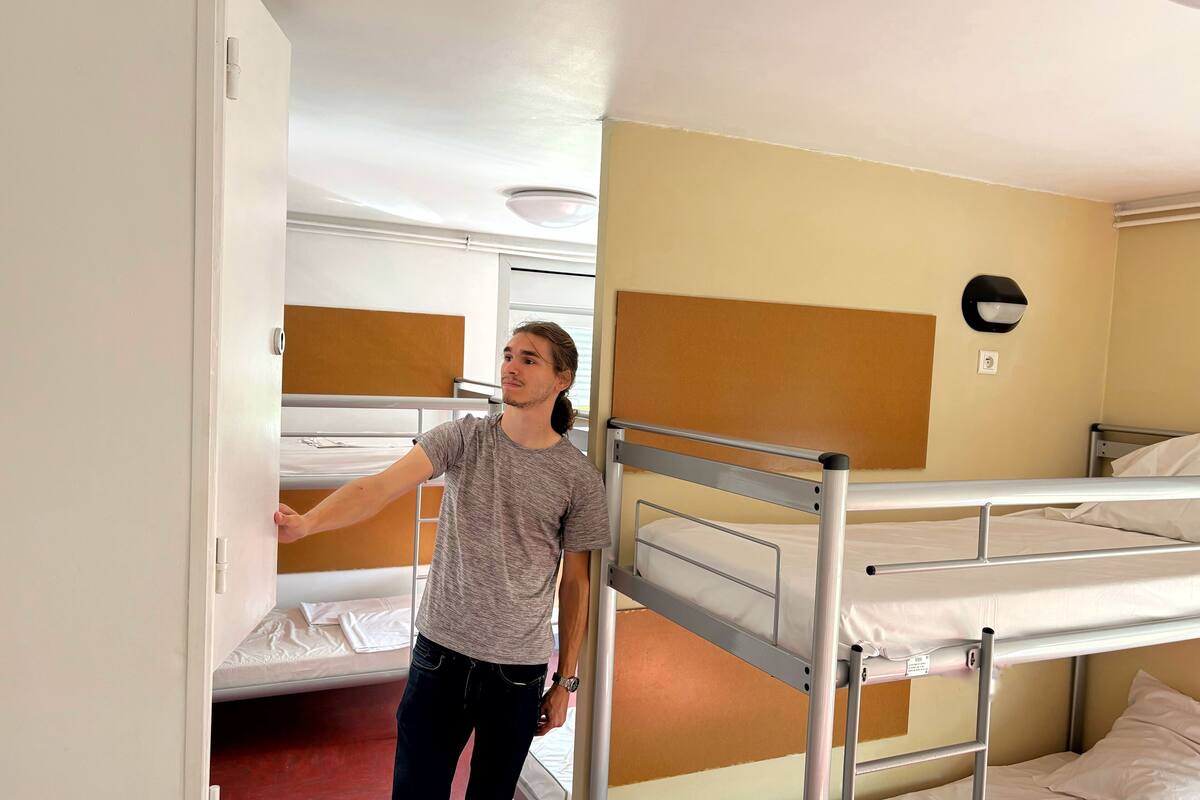 A hotel room with bunk beds, a wall-mounted light fixture, and a visible power outlet.
