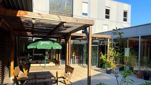 Un patio al aire libre con bancos de madera y un paraguas verde con la etiqueta "Perrier".