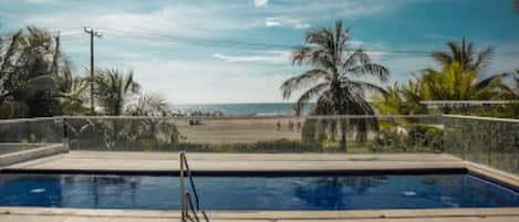 Una piscina con vista a la playa y palmeras.