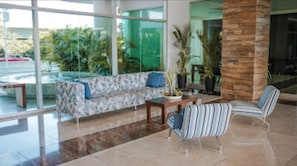Eine moderne Lobby mit einer Couch, gestreiften Sesseln, einem Couchtisch und Topfpflanzen.