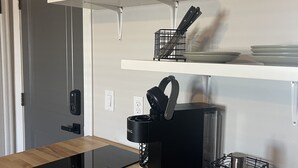 A modern kitchen with a black induction cooktop, a coffee maker, and a dishwasher. - Apartment 202 (Cando)