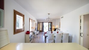 Una cocina moderna con una isla central, armarios blancos y vista al área de comedor.
