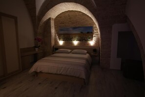 A bedroom with a stone archway, a bed, and a nightstand with a lamp. - B&B Arco Caputi (Ruvo di Puglia)