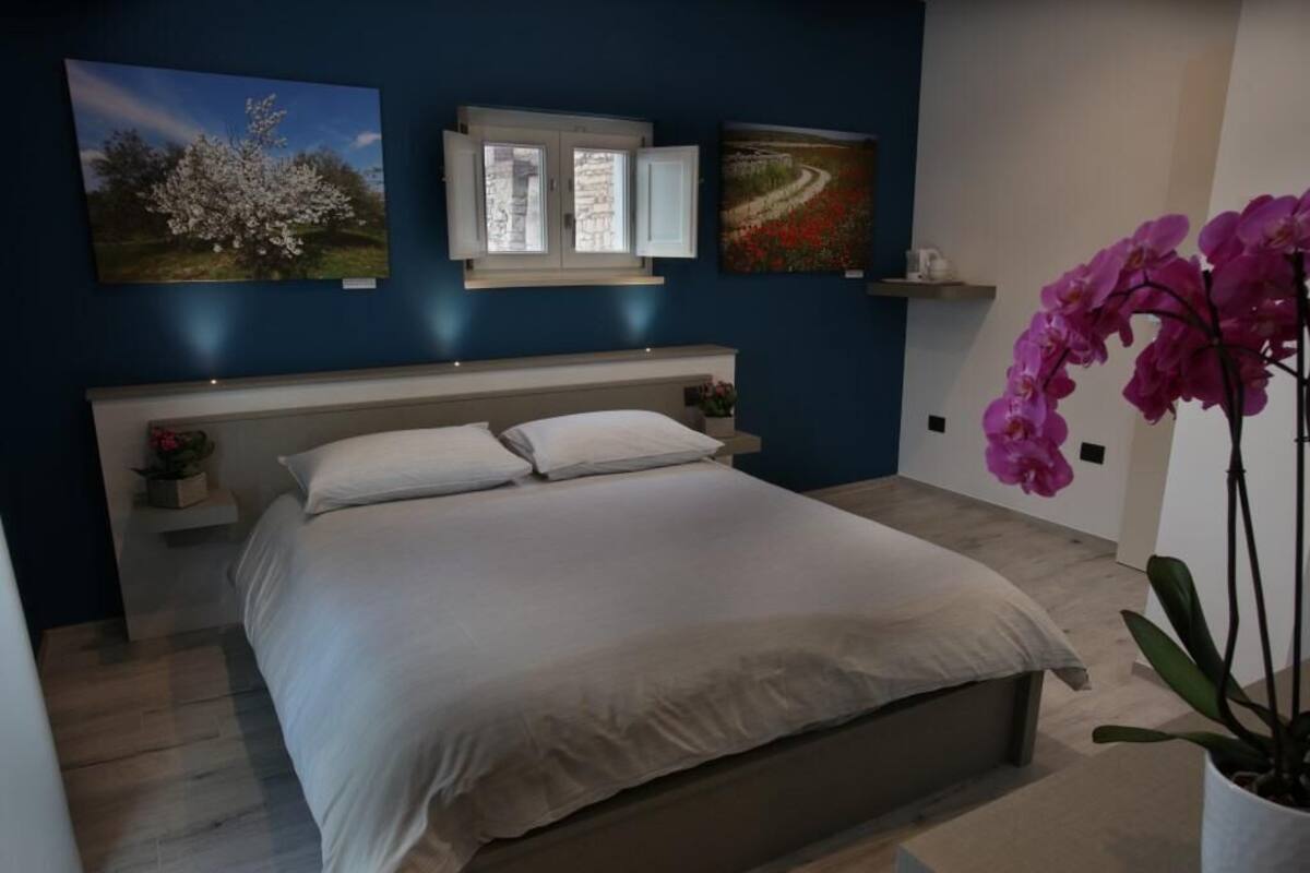 A bedroom with a bed, nightstands, a window, and wall art.