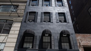 A building with a blue door labeled "The Flat" and a garage door. - The Flat NYC (New York)