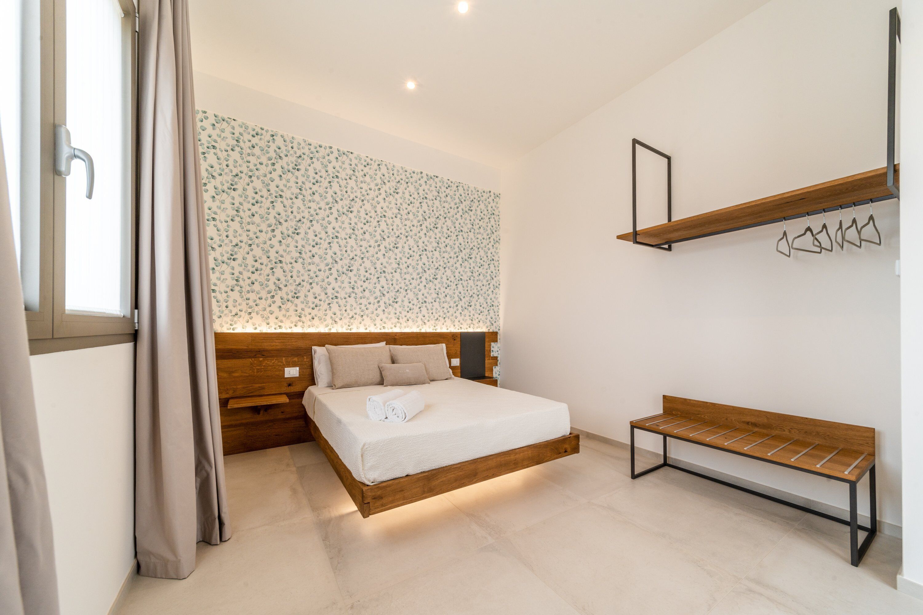 Un dormitorio moderno con una cama de madera, un banco y un estante de pared.
