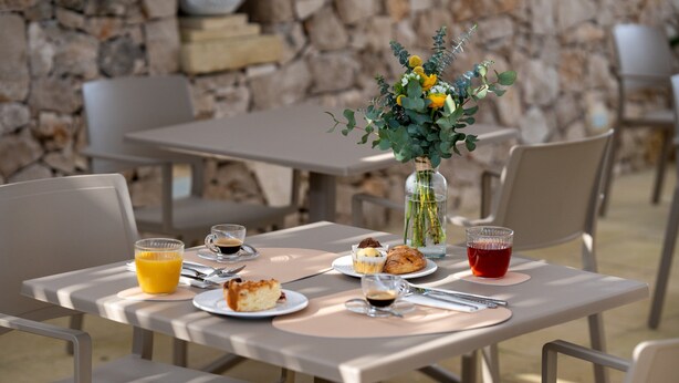 A table set for breakfast with a vase of flowers, plates of food, and drinks. - Sarmenti Agriresort (Otranto)