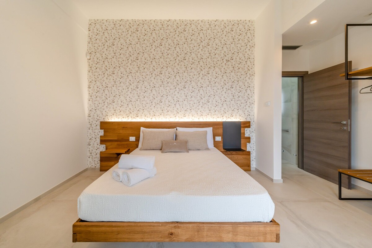 Une chambre à coucher moderne avec un cadre de lit en bois, un matelas blanc et un papier peint à motifs floraux.