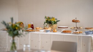 A breakfast buffet with various pastries, a fruit basket, and a vase of flowers. - Sarmenti Agriresort (Otranto)