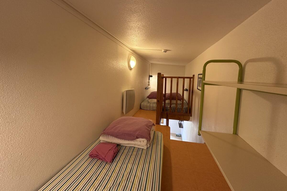 A narrow room with a bunk bed and a single bed.