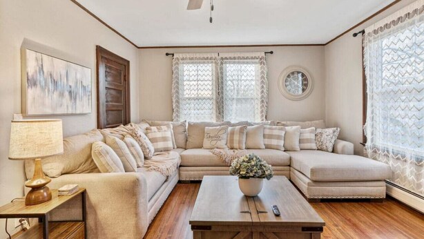 A living room with a sectional sofa, a wooden coffee table, a lamp, and a ceiling fan.