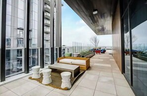 Relax on the outdoor terrace with a bench, stools, and a small table, surrounded by a city view.