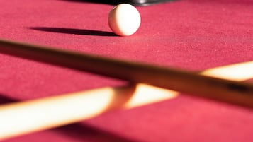 A close-up of a pool table with a cue stick and billiard balls.