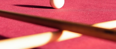 A close-up of a pool table with a cue stick and billiard balls.