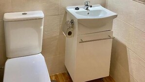 A bathroom with a toilet, sink, mirror, and tiled walls. - Mirasierra Center - Metro Usera 02 (1 bedroom apartment) (Madrid)