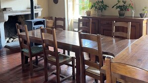 A rustic dining area with wooden tables and chairs, a fireplace, and potted plants. - La Maison Du Canal (Clamerey)