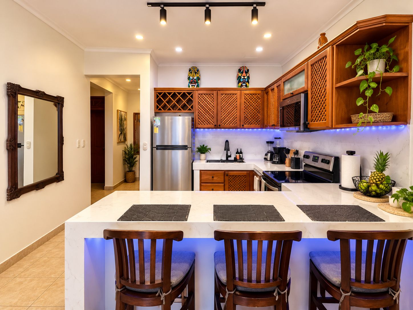 Une cuisine moderne dotée d’un îlot central, de meubles en bois, d’un réfrigérateur en acier inoxydable et d’un four à micro-ondes.