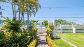 A pathway leading to a gated entrance with lush greenery and palm trees.