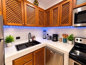 A kitchen with wooden cabinets, a stainless steel refrigerator, a dishwasher, a stove, and a coffee maker.