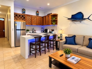Una cocina moderna con una isla central, armarios de madera y un pez decorativo azul en la pared.
