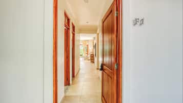 A hallway with wooden doors and a tiled floor, leading to a room with a window.
