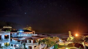 Een strandhotel met meerdere balkons, een zwembad en een goed verlicht buitengebied.
