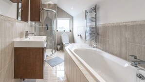 Un baño moderno con una bañera grande, una ducha con cerramiento de vidrio, un inodoro y un lavamanos.