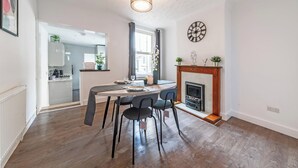 Un comedor con una mesa, sillas, una chimenea y un reloj en la pared.